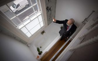 Estate agent David Myers leads a tour of what is dubbed 'London's thinnest house' in west London on February 5, 2021. - Wedged neatly between a doctor's surgery and a shuttered hairdressing salon, the five floor house in Shepherds Bush is just 5ft 6ins (1.6 metres) at its narrowest point and is currently on the market for £950,000 ($1,300,000, 1,100,000 euros). The unusual property, originally a Victorian hat shop with storage for merchandise and living quarters on its upper floors, was built sometime in the late 19th or early 20th century. (Photo by Tolga Akmen / AFP) (Photo by TOLGA AKMEN/AFP via Getty Images)