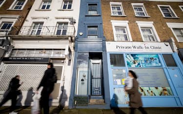 People walk past the front of what is dubbed 'London's thinnest house' (painted blue) in west London on February 5, 2021. - Wedged neatly between a doctor's surgery and a shuttered hairdressing salon, the five floor house in Shepherds Bush is just 5ft 6ins (1.6 metres) at its narrowest point and is currently on the market for £950,000 ($1,300,000, 1,100,000 euros). The unusual property, originally a Victorian hat shop with storage for merchandise and living quarters on its upper floors, was built sometime in the late 19th or early 20th century. (Photo by Tolga Akmen / AFP) (Photo by TOLGA AKMEN/AFP via Getty Images)