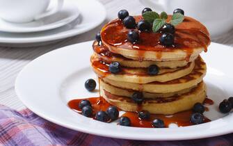 American Pancake with blueberries and maple syrup on a white plate horizontal