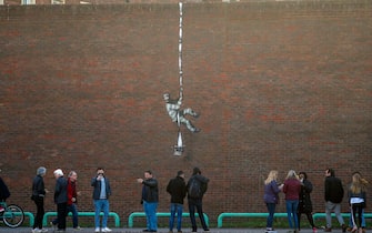 People take photographs of an artwork which has appeared on the wall of the former prison in Reading, Berkshire. Picture date: Monday March 1, 2121. PA Photo. Although its has not been officially claimed as the work of Banksy, the picture bares a resemblance to the artists other works. Photo credit should read: Steve Parsons/PA Wire (Photo by Steve Parsons/PA Images via Getty Images)