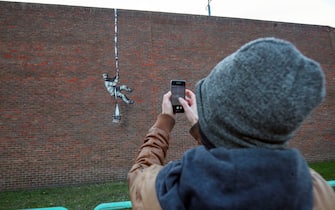 People take photographs of an artwork which has appeared on the wall of the former prison in Reading, Berkshire. Picture date: Monday March 1, 2121. PA Photo. Although its has not been officially claimed as the work of Banksy, the picture bares a resemblance to the artists other works. Photo credit should read: Steve Parsons/PA Wire (Photo by Steve Parsons/PA Images via Getty Images)