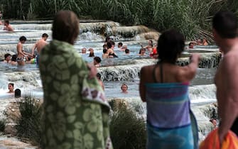 GROSSETO, ITALY - MAY 28:  People enjoy Saturnia's Thermal Baths located south of Tuscany in the area known as Maremma on May 28, 2012 in Grosseto, Italy. Use of the thermal baths of Saturnia date back to the Etruscans, whose  remains have been found in the area. The Romans also appreciated the baths, making them a rest station along the Via Clodia. The thermal waters have a constant temperature of 37.5 C, giving them therapeutic and relaxing properties. (Photo by Franco Origlia/Getty Images)