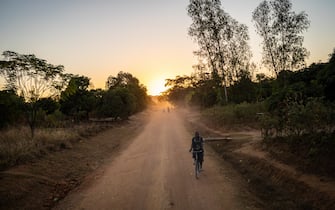 A personal travels down a rural road at sunset in Malawi's Mongochi District on 17 June 2017.  (Photo by John Fredricks/NurPhoto via Getty Images)