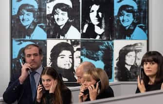 Sotheby's staff take calls for off-site bids, in front of Andy Warhol's "Sixteen Jackies", during an auction of The Macklowe Collection, at Sotheby's on November 15, 2021 in New York City. - RESTRICTED TO EDITORIAL USE - MANDATORY MENTION OF THE ARTIST UPON PUBLICATION - TO ILLUSTRATE THE EVENT AS SPECIFIED IN THE CAPTION (Photo by Yuki IWAMURA / AFP) / RESTRICTED TO EDITORIAL USE - MANDATORY MENTION OF THE ARTIST UPON PUBLICATION - TO ILLUSTRATE THE EVENT AS SPECIFIED IN THE CAPTION / RESTRICTED TO EDITORIAL USE - MANDATORY MENTION OF THE ARTIST UPON PUBLICATION - TO ILLUSTRATE THE EVENT AS SPECIFIED IN THE CAPTION (Photo by YUKI IWAMURA/AFP via Getty Images)