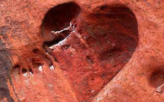 A heart-shaped cave etched by wind and water adorns the face of Uluru (Ayers Rock) in the World Hertage-listed Uluru-Kata Tjuta National Park encompassing 1,325 square kms of desert in Central Australia, 12 November 2005. Uluru, the largest single rock in the world, is made of arkose -- a coarse sandstone rich in feldspar.  AFP PHOTO/Torsten BLACKWOOD (Photo credit should read TORSTEN BLACKWOOD/AFP via Getty Images)