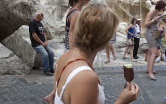 Una turista mangia un gelato confezionato a piazza fontana di Trevi a Roma oggi 04 luglio 2011. Il gelato si conferma re del'estate: sono 23 milioni gli italiani che consumano coni, coppette o stecchi fuori delle mura domestiche durante la stagione estiva e il 33% lo fa "per coccolarsi". E' quanto emerge da un'indagine Eurisko/Igi (Istituto del gelato italiano) che mette anche in rilievo come finisca in parità il 'derby' tra gelato artigianale e quello confezionato: il 98% dei consumatori italiani acquista entrambe le tipologie. 
ANSA/LUCIANO DEL CASTILLO