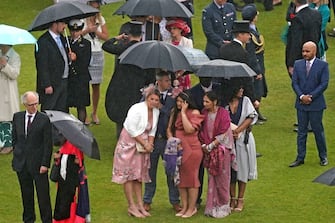 Guests shelter from the rain beneath umbrellas as they attend a Royal Garden Party at Buckingham Palace in London on May 25, 2022. (Photo by Aaron Chown / POOL / AFP) (Photo by AARON CHOWN/POOL/AFP via Getty Images)