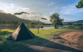 Outdoor camping tent among meadow on mountain during sunrise at Kanchanaburi province in Thailand