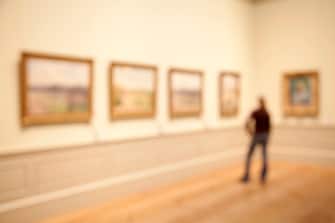 Young woman observing a row of paintings in a gallery.