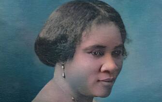 Colorized studio portrait of Madam C J Walker, wearing a fringe-trimmed dress and posing with her face turned toward the camera in three-quarter-profile view, attributed to Scurlock Studio, Washington, DC, 1914. Note: Image has been digitally colorized using a modern process. Colors may not be period-accurate. (Photo by Gado/Getty Images)