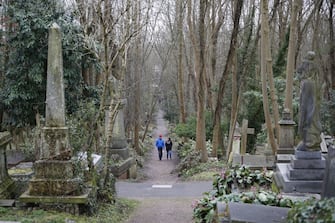 Visitors walk by graves in Highgate Cemetery in north London on February 5, 2019. (Photo by Tolga AKMEN / AFP) (Photo by TOLGA AKMEN/AFP via Getty Images)