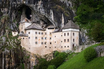 TOPSHOT - This photograph taken on May 25, 2021, shows the Predjama Castle, a Renaissance construction built within a cave mouth near Postojna. - The grass flickered gently above a crack in the limestone and Ludvik Husu instinctively knew he had found what he was searching for: a new cave in Slovenia's dramatic Karst region. The tiny Alpine nation is unusually rich in such caves, which are a major tourist bonanza and have also been put to uses as varied as building a major medieval castle or hosting astronauts sent by the European Space Agency. (Photo by Jure Makovec / AFP) (Photo by JURE MAKOVEC/AFP via Getty Images)