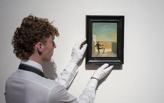 LONDON, UNITED KINGDOM - OCTOBER 14: An art handler holds a painting titled 'Le spectre de Vermeer de Delft' by Salvador Dali (estimate: $4,000,000-6,000,000) during a photo call to present the highlights from the estate of the philanthropist and co-founder of Microsoft, Paul G. Allen in London, United Kingdom on October 14, 2022. The collection of over 150 masterpieces, valued in excess of $1 Billion, will be offered at an auction on 9 and 10 November at Rockefeller Center in New York, with all proceeds dedicated to philanthropic causes. (Photo by Wiktor Szymanowicz/Anadolu Agency via Getty Images)