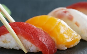 Macro shot of sushi,sashimi,uramaki and nighiri.typical Japanese dish consisting of rice, salmon or tuna,shrimp and fish eggs on a black background.Concept:Japanese restaurant,sushi,oriental tradition