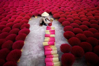 1078902448 TOPSHOT - This picture taken on January 3, 2019 shows a Vietnamese woman collecting incense sticks in a courtyard in the village of Quang Phu Cau on the outskirts of Hanoi. - In Vietnam's 'incense village', hundreds of workers are hard at work dying, drying and whittling down bamboo bark to make the fragrant sticks ahead of the busy lunar new year holiday. (Photo by Manan VATSYAYANA / AFP) / TO GO WITH Vietnam-lifestyle-holiday-religion-craft, PHOTOESSAY by Manan Vatsyayana (Photo by MANAN VATSYAYANA/AFP via Getty Images)