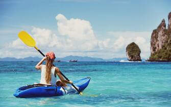 Travel concept with single girl on kayak at tropical bay