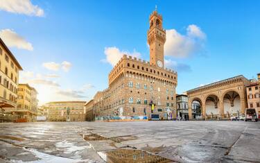 Florence, Italy. View of Piazza della Signoria square with Palazzo Vecchio reflecting in a puddle at sunrise