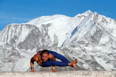 French Alps. Mont-Blanc massif. Woman doing yoga meditation on mountain. Saint-Gervais, France. (Photo by: Godong/Universal Images Group via Getty Images)