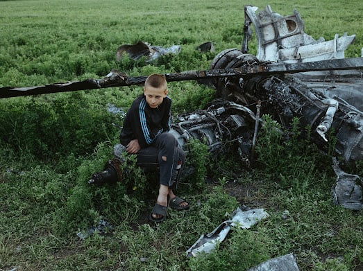Oleksiy Polyakov, right, and Roman Voitko check the remains of a destroyed Russian helicopter lie in a field in the village of Malaya Rohan, Kharkiv region, Ukraine, Sunday, May 15, 2022.