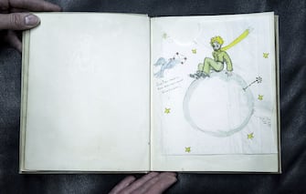 A drawing from an original color signed copy of "Le Petit Prince" by late French author and aviator Antoine de Saint-Exupery, is pictured at the Cazo auction house on December 2, 2016 in Paris, on the eve of their sale.
On December 3, Maison Cazo will be selling an original and signed copy of the Petit Prince which will be accompanied by two drawings by author Antoine de Saint-Exupery. The copy for sale at Cazo is an original color edition of the French version of the Little Prince published in New York in 1943 by Reynal & Hitchcock. This unpublished copy dedicated and accompanied by two original drawings is estimated by Cazo to sell between 80,000 and 100,000 euros. / AFP / PHILIPPE LOPEZ / RESTRICTED TO EDITORIAL USE - MANDATORY MENTION OF THE ARTIST UPON PUBLICATION - TO ILLUSTRATE THE EVENT AS SPECIFIED IN THE CAPTION        (Photo credit should read PHILIPPE LOPEZ/AFP via Getty Images)