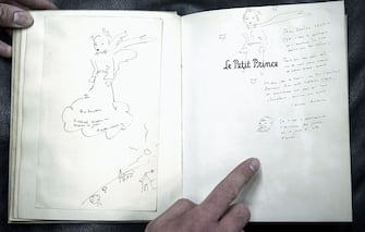 An original and signed copy of "Le Petit Prince" by late French author and aviator Antoine de Saint-Exupery, featuring a dedication to Doudou Chassin, is pictured at the Cazo auction house on December 2, 2016 in Paris, on the eve of their sale.
On December 3, Maison Cazo will be selling an original and signed copy of the Petit Prince which will be accompanied by two drawings by author Antoine de Saint-Exupery. The copy for sale at Cazo is an original color edition of the French version of the Little Prince published in New York in 1943 by Reynal & Hitchcock. / AFP / Philippe LOPEZ / RESTRICTED TO EDITORIAL USE - MANDATORY MENTION OF THE ARTIST UPON PUBLICATION - TO ILLUSTRATE THE EVENT AS SPECIFIED IN THE CAPTION        (Photo credit should read PHILIPPE LOPEZ/AFP via Getty Images)