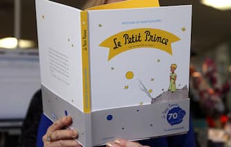 A woman reads a new edition of "The Little Prince" book on April 11, 2013 in Paris. France is marking the 70th anniversary of the world-loved "The Little Prince" with a host of special editions, including a new biography of its author, native son Antoine de Saint-Exupery. "Le Petit Prince", a series of parables in which a boy prince recounts his adventures among the stars to a downed pilot on Earth, was first published in New York in 1943, in English and French.   AFP PHOTO / PATRICK KOVARIK        (Photo credit should read PATRICK KOVARIK/AFP via Getty Images)