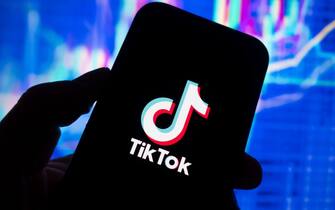 Digital composite image of TikTok social media app logo on phone scree.