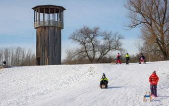 Recklinghausen, North Rhine-Westphalia, Germany - Sunny winter landscape in the Ruhr area, Emscherkunst in the snow, Kawamata Tower on the Emscher, WALKWAY AND TOWER, 2010, by Tadashi Kawamata, children ride sledges.