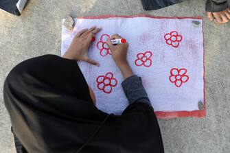 epa10502426 A woman draws a flower pattern during a workshop on how to turn plastic waste into useful items, in Banda Aceh, Indonesia, 04 March 2023. The training was initiated by a local community center called KamiKita, a non-profit organization that focuses on waste processing and urban farming in Banda Aceh, with the aim of educating the public to recycle and give plastic a second life.  EPA/HOTLI SIMANJUNTAK