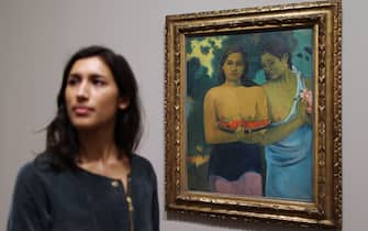 LONDON, ENGLAND - SEPTEMBER 28:  An Tate employee stands next to 'Two Tahitian Women 1899' at The Gauguin exhibition at The Tate Modern on September 28, 2010 in London, England. Exhibited together for the first time in the UK in over 50 years this collection of Paul Gauguin's paintings, sketches and sculptures will open to the public on September 30, 2010 and will run until January 16, 2011.  (Photo by Peter Macdiarmid/Getty Images)