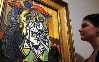 An employee poses next to a 1937 painting by Spanish artist Pablo Picasso entitled 'Weeping Woman' during the press preview of the 'Picasso and Modern British Art' exhibition at the Tate gallery in London on February 13, 2012. The exhbition will run from February 15 to July 15.  AFP PHOTO / CARL COURT (Photo credit should read CARL COURT/AFP via Getty Images)