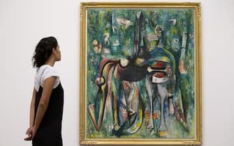 A gallery assistant poses with artwork entitled "The Sombre Malembo 1943" by Cuban Surrealist painter, Wifredo Lam, during a photocall to promote an exhibition of the artist's work, at Tate Modern gallery in London on September 13, 2016.
The exhibition is set to run from September 14, 2016, until January 8, 2017. / AFP / JUSTIN TALLIS / RESTRICTED TO EDITORIAL USE - MANDATORY MENTION OF THE ARTIST UPON PUBLICATION - TO ILLUSTRATE THE EVENT AS SPECIFIED IN THE CAPTION        (Photo credit should read JUSTIN TALLIS/AFP via Getty Images)