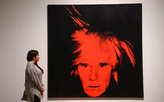 A gallery assistant poses with an artwork entitled "Self Portrait, 1986", by US artist Andy Warhol during a press preview for the forthcoming Andy Warhol exhibition at the Tate Modern in London on March 10, 2020. - The exhibition is set to run from March 12 to September 6. (Photo by Justin TALLIS / AFP) / RESTRICTED TO EDITORIAL USE - MANDATORY MENTION OF THE ARTIST UPON PUBLICATION - TO ILLUSTRATE THE EVENT AS SPECIFIED IN THE CAPTION (Photo by JUSTIN TALLIS/AFP via Getty Images)