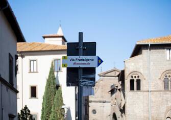 Road sign for the Via Francigena, an ancient pilgrimage walk between Canterbury and  Rome. In the background the cathedral in Viterbo can be seen.