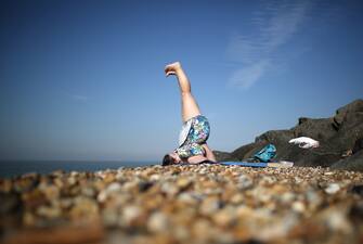 179564795 SHEERNESS, ENGLAND - SEPTEMBER 05: A woman practices yoga on the beach on September 5, 2013 in Sheerness, England. Southern England is enjoying a couple of days of late summer sunshine with temperatures today expected to peak at 30C, before predicted rain and cooler temperatures are pushed in tonight. (Photo by Peter Macdiarmid/Getty Images)