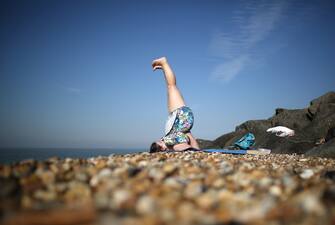 SHEERNESS, ENGLAND - SEPTEMBER 05:  A woman practices yoga on the beach on September 5, 2013 in Sheerness, England. Southern England is enjoying a couple of days of late summer sunshine with temperatures today expected to peak at 30C, before predicted rain and cooler temperatures are pushed in tonight.  (Photo by Peter Macdiarmid/Getty Images)