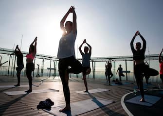 People practice yoga on the top of the Montparnasse Tower on July 4, 2017 in Paris.  / AFP PHOTO / GEOFFROY VAN DER HASSELT        (Photo credit should read GEOFFROY VAN DER HASSELT/AFP via Getty Images)