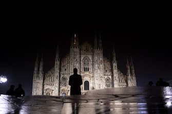 TOPSHOT - A man walking by the cathedral is reflecting in a puddle at Piazza Duomo, on  November 25, 2017 in Milan.  / AFP PHOTO / MARCO BERTORELLO        (Photo credit should read MARCO BERTORELLO/AFP via Getty Images)