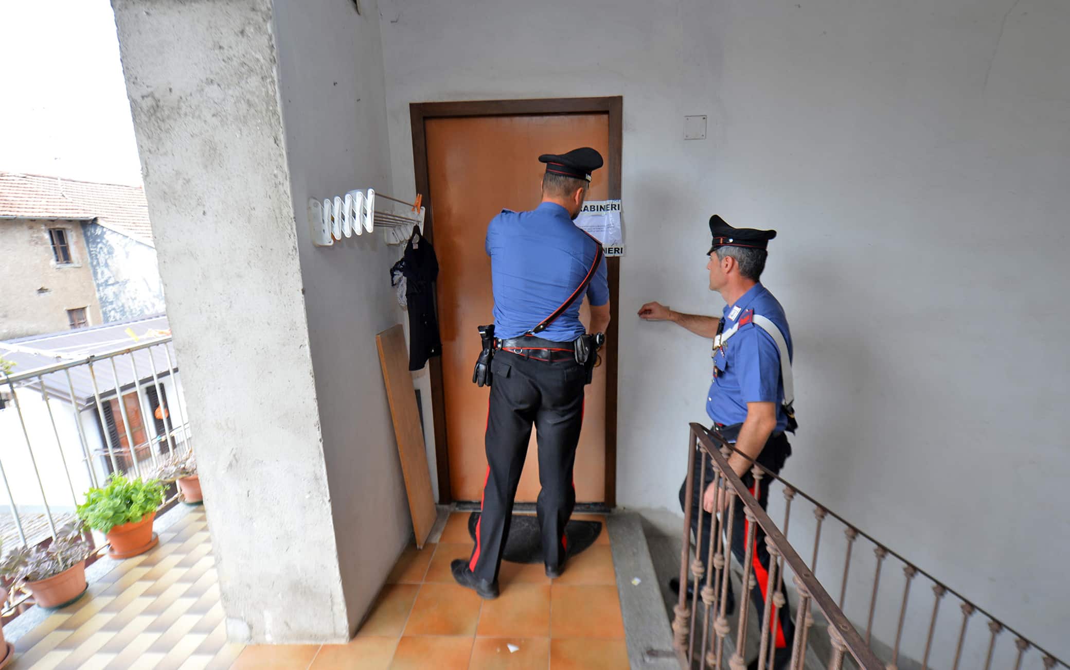 I carabinieri davanti l'ingresso dell'abitazione di Carmela Fabozzi la donna di 73 anni trovata morta nel suo appartamento di Malnate (Varese), 23 luglio 2022. 
ANSA/Agenzia Blitz Varese