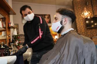 BERLIN, GERMANY - MAY 04: A barber tends to a customer as both of them wear protective face masks at a barber shop open for the first day since March during the novel coronavirus crisis on May 4, 2020 in Berlin, Germany. Barber shops and hair salons are reopening this week nationwide as authorities carefully lift lockdown measures that had been imposed to stem the spread of the virus. (Photo by Sean Gallup/Getty Images)