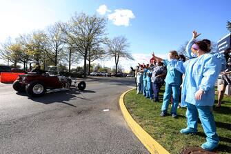 EAST MEADOW, NEW YORK - MAY 04:  Healthcare workers wave as a parade of classic cars makes its way by Nassau University Medical Center in a salute to workers on the front lines of the COVID-19 pandemic on May 04, 2020 in East Meadow, New York. (Photo by Al Bello/Getty Images)