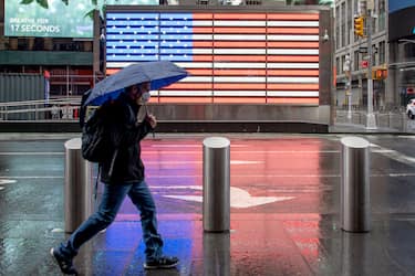 NEW YORK, NEW YORK - MAY 06: A man wearing a mask walks with an umbrella in Times Square near the American Flag amid the coronavirus pandemic on May 6, 2020 in New York City. COVID-19 has spread to most countries around the world, claiming over 263,000 lives with over 3.8 million cases. (Photo by Alexi Rosenfeld/Getty Images)