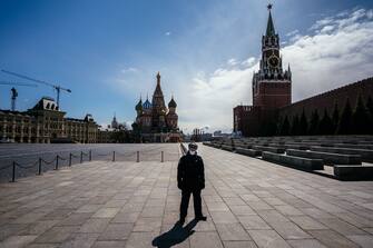 1210641495 A law enforcement officer stands guard on the deserted Red Square in front of St. Basil's Cathedral and the Kremlin's Spasskaya Tower in downtown Moscow on April 22, 2020, during a strict lockdown in Russia to stop the spread of the novel coronavirus COVID-19. (Photo by Dimitar DILKOFF / AFP) (Photo by DIMITAR DILKOFF/AFP via Getty Images)