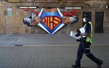 epa08405136 A masked man passes a mural by Lionel Stanhope in support of Britain's National Health Service (NHS) in London, Britain, 06 May 2020. Countries around the world are taking increased measures to stem the widespread of the SARS-CoV-2 coronavirus which causes the Covid-19 disease.  EPA/NEIL HALL