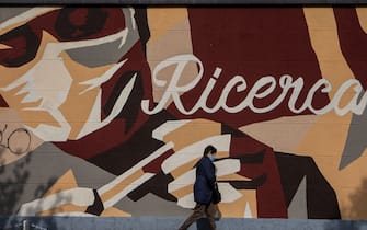MILAN, ITALY - APRIL 30: A woman walks past a mural representing a medical worker handling a swab and reading 'Research' on April 30, 2020 in Milan, Italy. Italy will remain on lockdown to stem the transmission of the Coronavirus (Covid-19), slowly easing restrictions. (Photo by Emanuele Cremaschi/Getty Images)