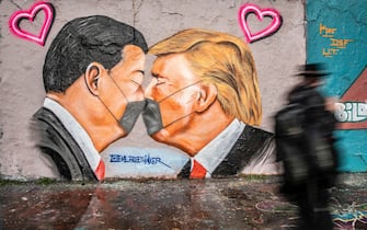 epa08392254 A man walks by a mural of US President Donald Trump (R) and Chinese President Xi Jinping kissing while surgical face masks at Mauerpark (Wall Park) in Berlin, Germany, 29 April 2020. The German government and local authorities are beginning to consider to gradually lift restrictions implemented to stem the spread of the coronavirus SARS-CoV-2 that causes the COVID-19 disease.  EPA/OMER MESSINGER
