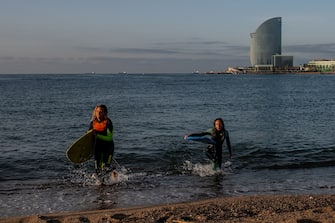 BARCELONA, SPAIN - MAY 08: Two women leaves the water after practicing surf at dawn at La Barceloneta Beach opened for the first day since March 15 during the novel coronavirus crisis on May 08, 2020 in Barcelona, Spain. Permitted activities now include outdoor water sports such as surfing, paddle boarding or swimming from 6 - 10 AM and from 8 - 11 PM, with beaches only open for sporting activities such as running, working out or water sports. Spain has had more than 220,000 confirmed cases of COVID-19 and over 26,000 reported deaths, although the rate has declined after weeks of lockdown measures.  (Photo by David Ramos/Getty Images)