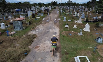 1212238253 Brazilian Ulisses Xavier, 52, who has worked for 16 years at Nossa Senhora cemetery in Manaus, Brazil, rides a bike as he arrives for his shift on May 7, 2020, amid the new coronavirus pandemic. - Xavier works 12 hours a day and supplements his income by making wooden crosses for graves. The cemetery has seen a surge in the number of new graves after the outbreak of COVID-19. (Photo by MICHAEL DANTAS / AFP) (Photo by MICHAEL DANTAS/AFP via Getty Images)