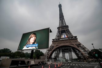 1212472650 A portrait of a doctor at the AP-HP (Assistance Publique - Hopitaux de Paris) who was mobilized during the COVID-19 pandemic and pictures of other representatives of professional groups are displayed during a tribute on a giant screen in front of The Eiffel Tower in Paris on May 10, 2020, on the eve of France's easing of lockdown measures in place for 55 days to curb the spread of the pandemic, caused by the novel coronavirus. (Photo by Thomas SAMSON / AFP) (Photo by THOMAS SAMSON/AFP via Getty Images)