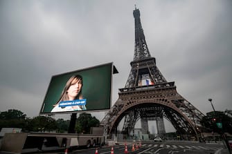 A portrait of a doctor at the AP-HP (Assistance Publique - Hopitaux de Paris) who was mobilized during the COVID-19 pandemic and pictures of other representatives of professional groups are displayed during a tribute on a giant screen in front of The Eiffel Tower in Paris on May 10, 2020, on the eve of France's easing of lockdown measures in place for 55 days to curb the spread of the pandemic, caused by the novel coronavirus. (Photo by Thomas SAMSON / AFP) (Photo by THOMAS SAMSON/AFP via Getty Images)